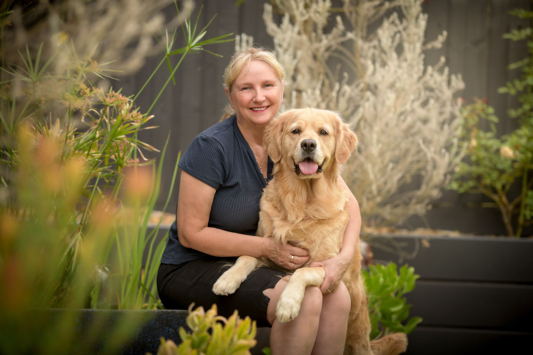 A woman in her garden with her golden retriever