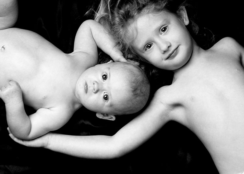 Twin babies lying head to head, in black and white