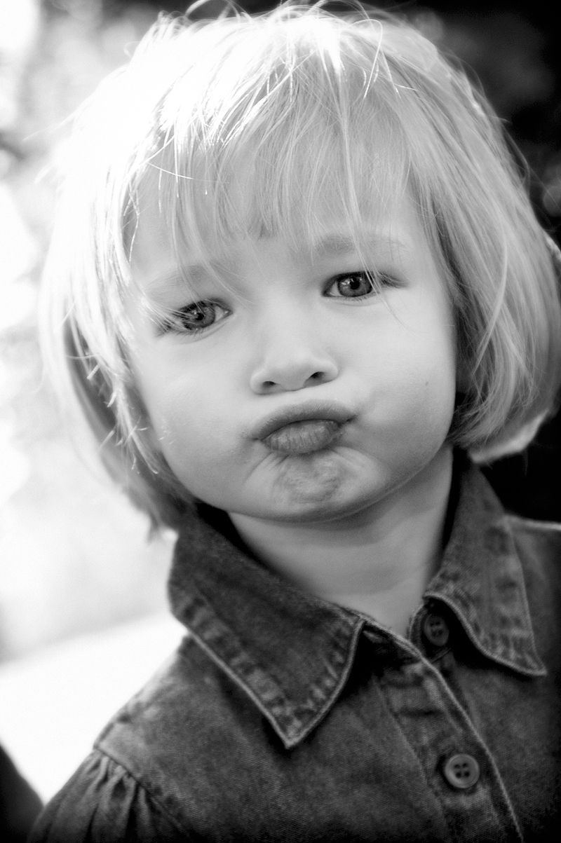 A toddler pulling a pout, in black and white