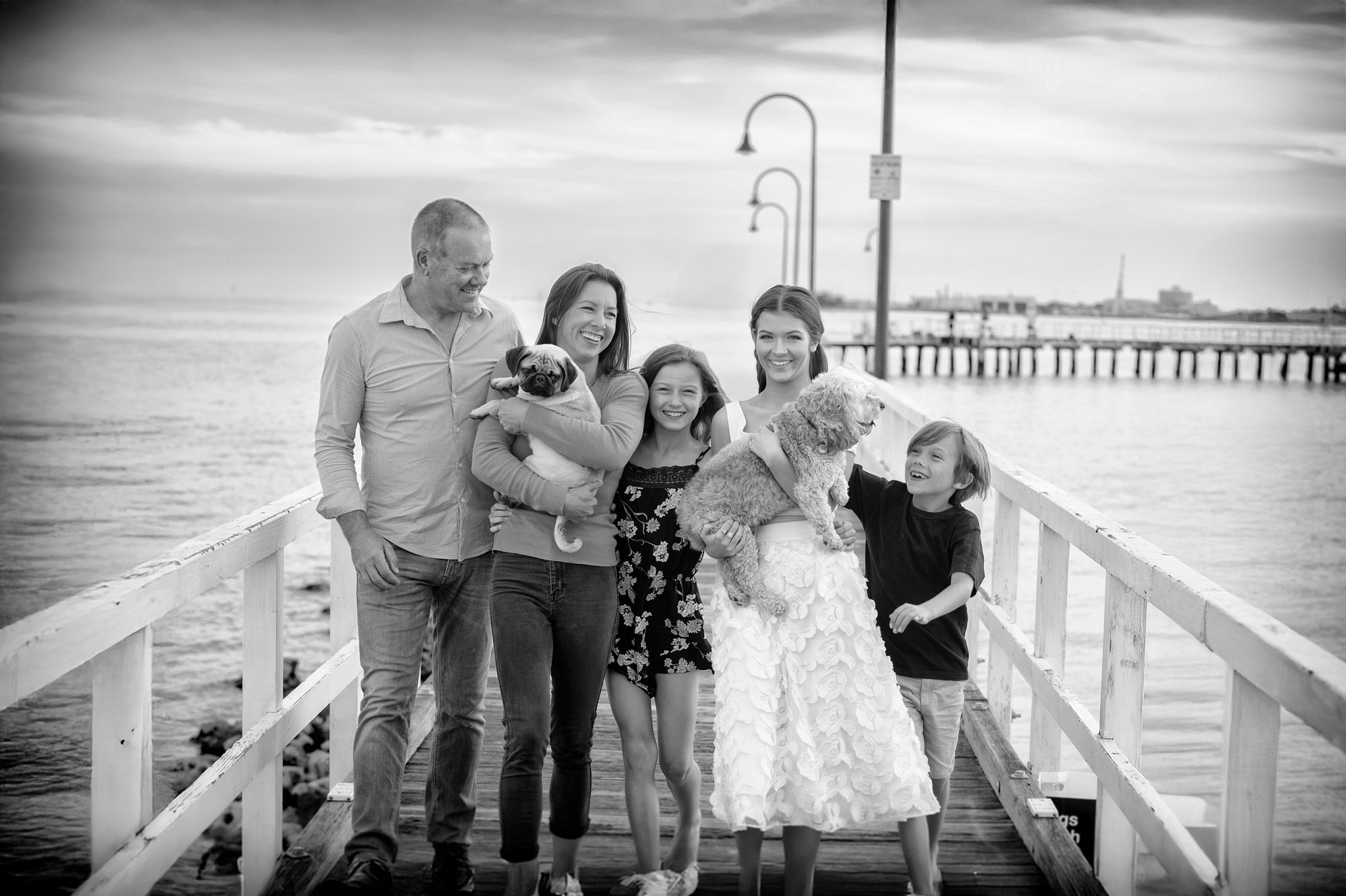 A family with their two small dogs on a pier