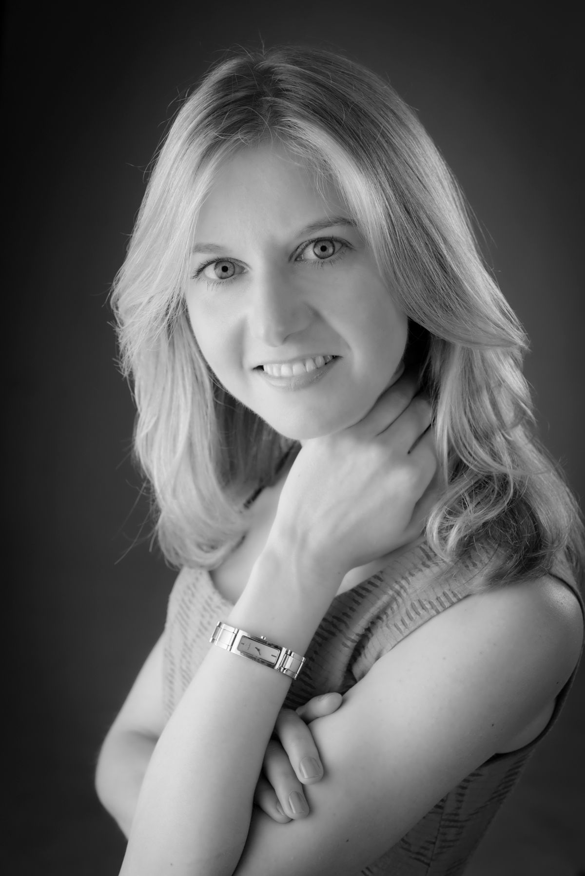 A woman with long hair looking gently past the camera, in black and white